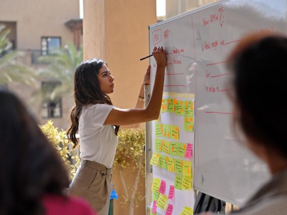 A student standing and writing on a white board