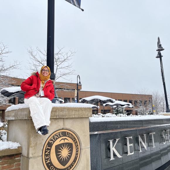 Girl sitting beside university sign