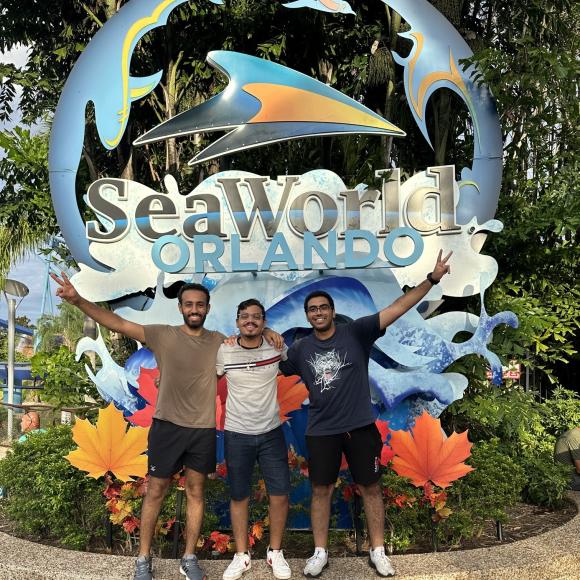 Three boys standing in front of a huge statue of sea world