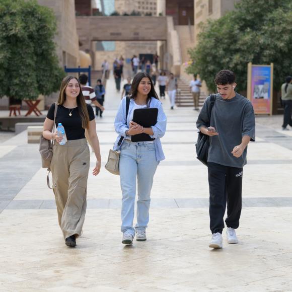 two girls and a boy walking together on campus