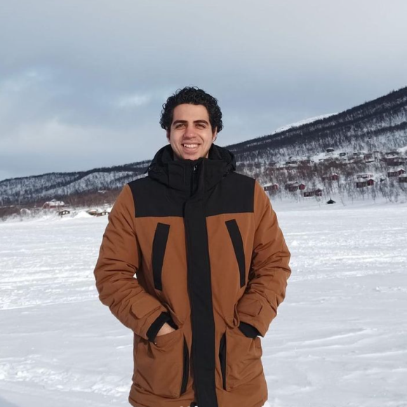 a male is standing in the snow, he is smiling