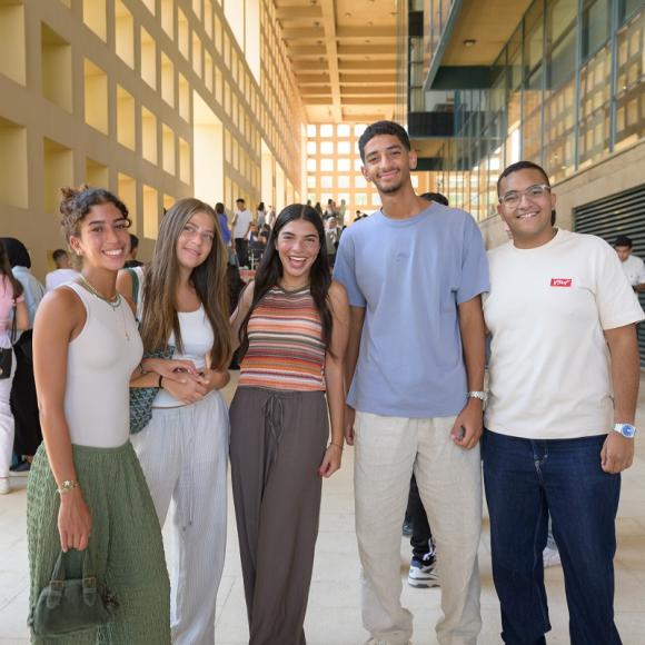 Two males and three females are standing together and smiling