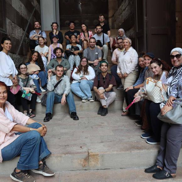 students sitting on stairs of islamic heritage site , posing for a photo