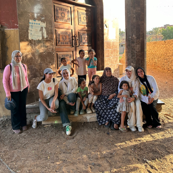 A group of students smiling and standing together with the local community at Qursaya Island