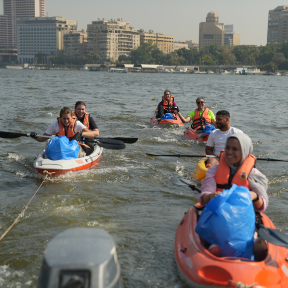 A group of students kayaking on boats in the Nile and picking up plastic waste from the Nile