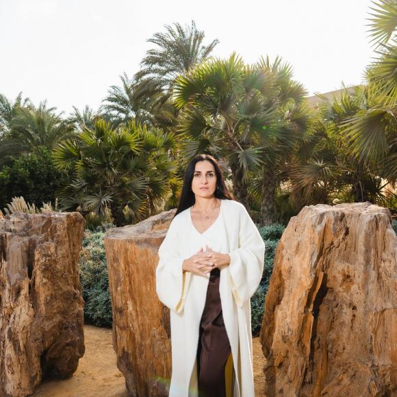 A female is standing in front of big rocks